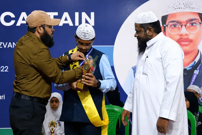 An elected student leader receiving a trophy and sash at the school captain ceremony