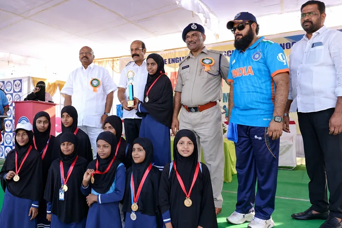 A group of students wearing their medals alongside officials at a sports meet