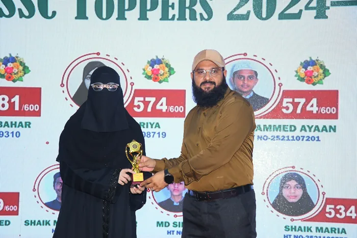 A Class X topper receiving a trophy in front of the SSC Toppers 2024 board