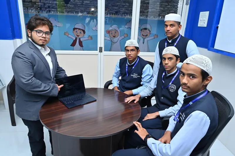 Students working on laptops with a teacher in the computer laboratory