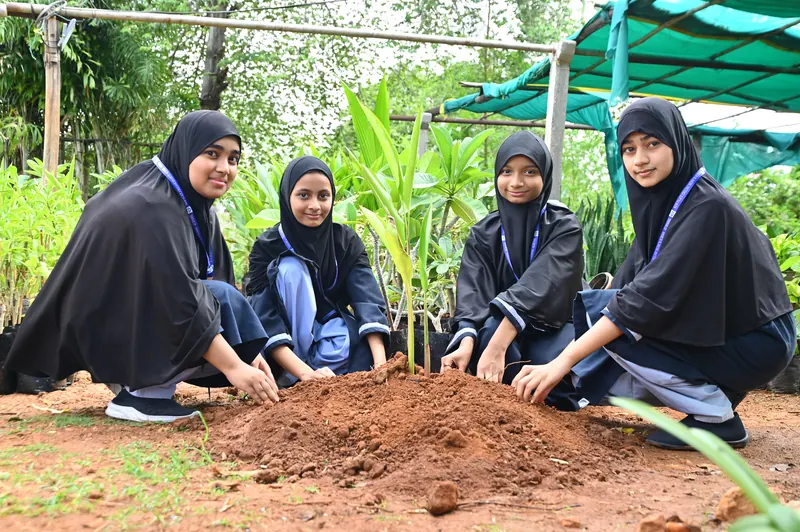 Students planting saplings in soil during the tree plantation drive