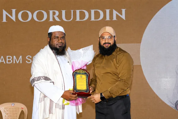 Dr. Shaik Nasir receiving a memento and bouquet on stage at a community education event