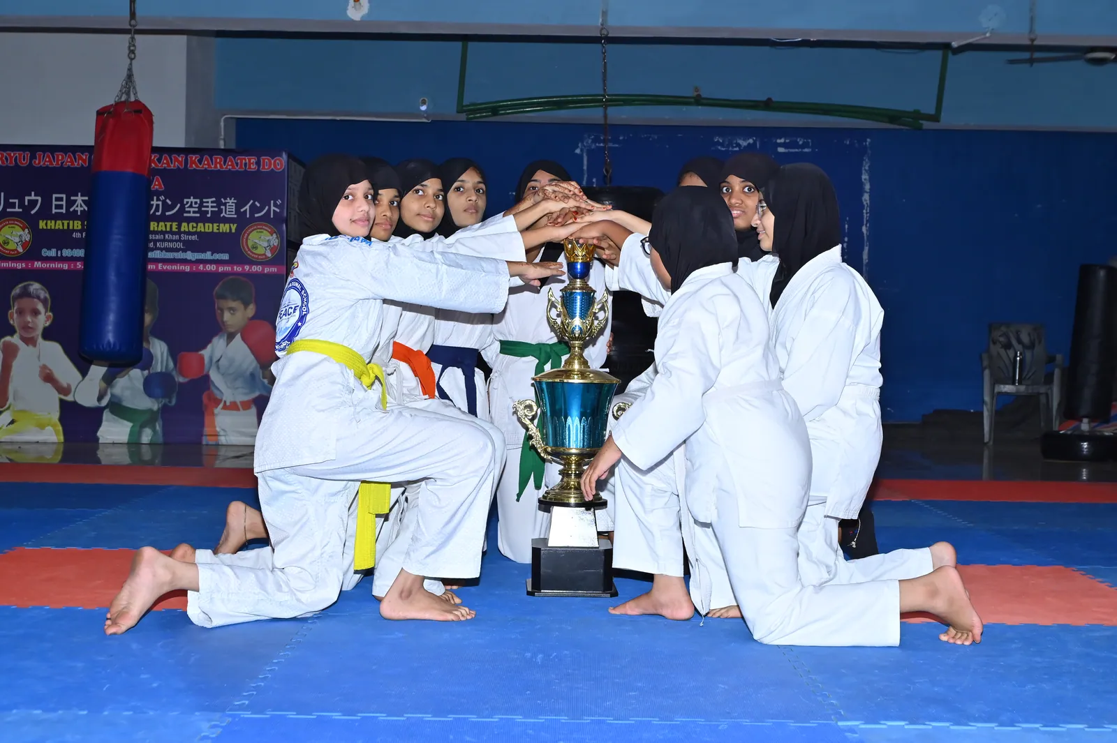 The school karate team celebrating with a championship trophy