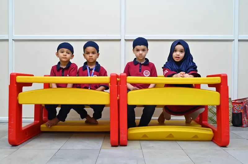 Younger students seated at their desks in the prescribed junior school uniform