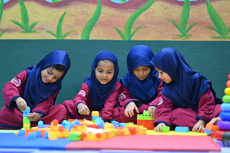 Kindergarten children playing with coloured building blocks