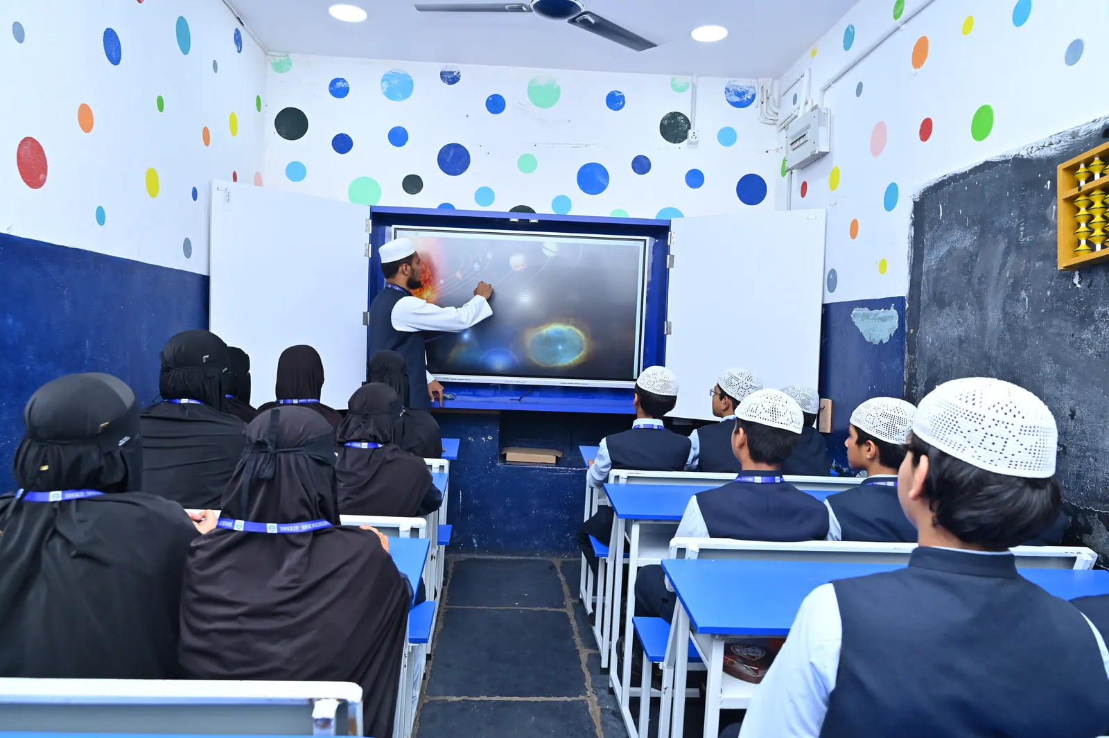 A classroom of students following an animated lesson on an LED interactive panel