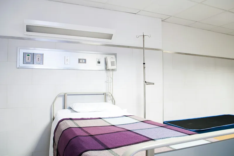 A made-up rest bed against a white tiled wall in the medical room