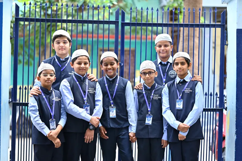 A group of students smiling together at the school gate
