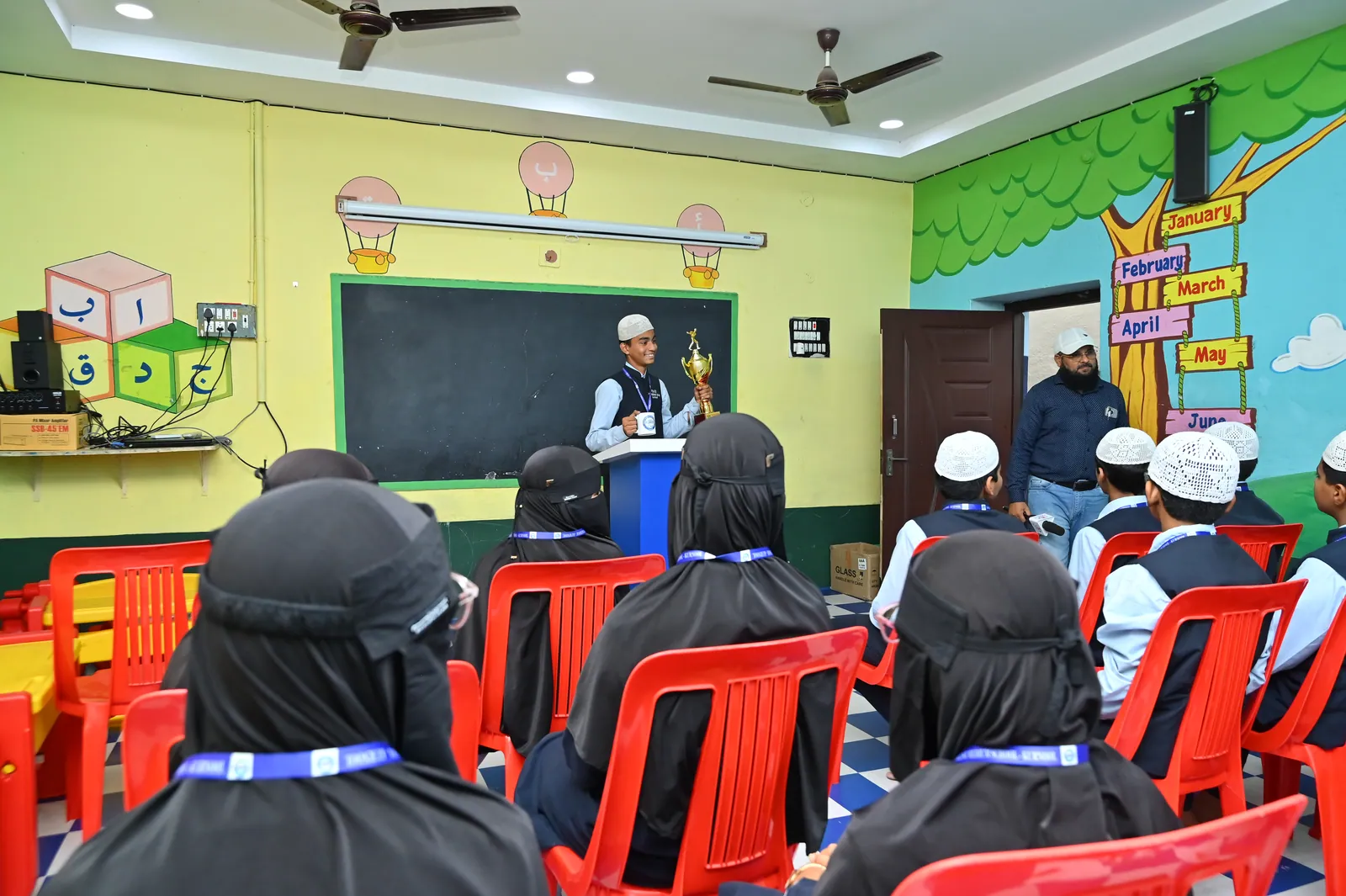 A student holding a competition trophy at Peace English Medium School